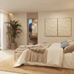 Dormitorio con cama en tonos arena, alfombra de yute, ventanal con vistas al mar y baño al fondo
