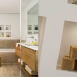 Baño con mueble de madera, bañera y piedra beige, junto al detalle de unos jabones en una hornacina