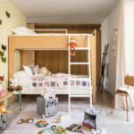 Dormitorio infantil con litera de madera y blanco, papel pintado amarillo geométrico y juguetes