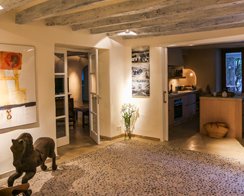 Casa de campo en Mallorca, interior con vigas de madera, suelo de guijarros y cocina al fondo
