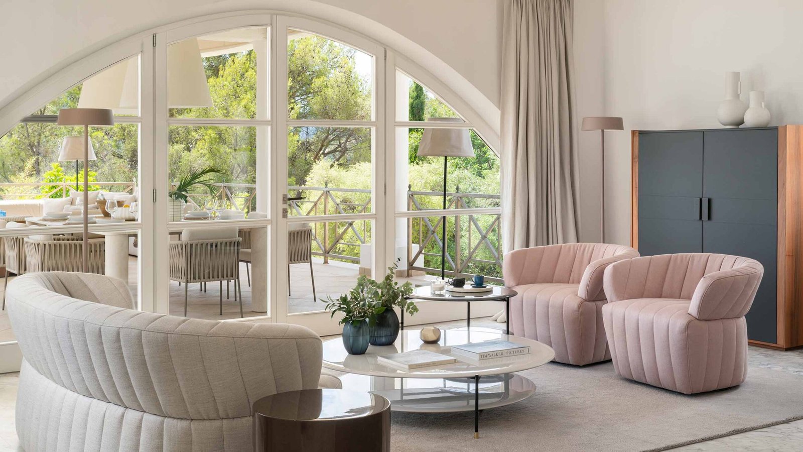 Zona de estar con mueble gris y madera, mesa de centro blanca y luz natural del ventanal