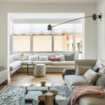 Zona de estar con banco corrido en la galería acristalada, sofá, estantería de roble y parqué en espiga