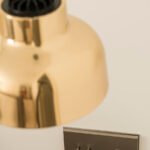 Detalle de lámpara colgante de latón pulido y mecanismo metálico con interruptores y toma USB en pared